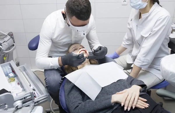Medico dentista tratta i denti di una bella ragazza paziente. La ragazza alla reception dal dentista. Medico dentista tratta dente. — Foto Stock