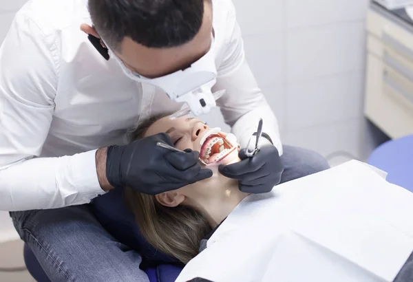 Doctor dentista trata los dientes de una hermosa joven paciente. La chica en recepción en el dentista. Médico dentista trata diente. —  Fotos de Stock