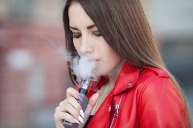 güzel bir kadın (vaping) e-sigara duman açık havada ile. Vaping kavramı.