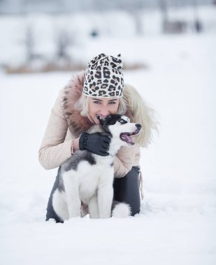 Mutlu gülen Beyaz sarışın kadın ve köpeğini Husky. Kış beyaz ormandaki açık havada birlikte oynama.