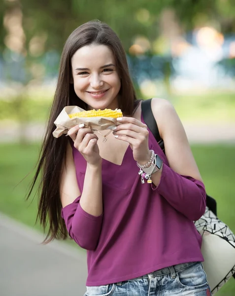 トウモロコシの穂軸を食べる若い美容女性の屋外のポートレート — ストック写真
