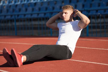 Adam beyaz gömlek stadyum alanında, egzersiz yapmak.