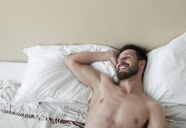 Kaygısız adam zevk yeni gün. Seksi, mutlu sakallı adam yatakta.