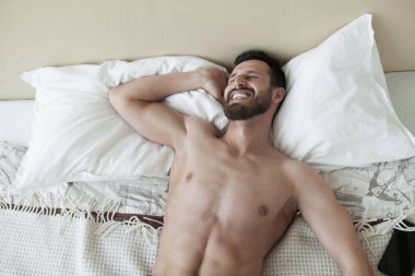 Kaygısız adam zevk yeni gün. Seksi, mutlu sakallı adam yatakta.