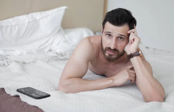 快乐放松的年轻人微笑着躺在床上 性感的大胡子男人在床上 — 图库照片