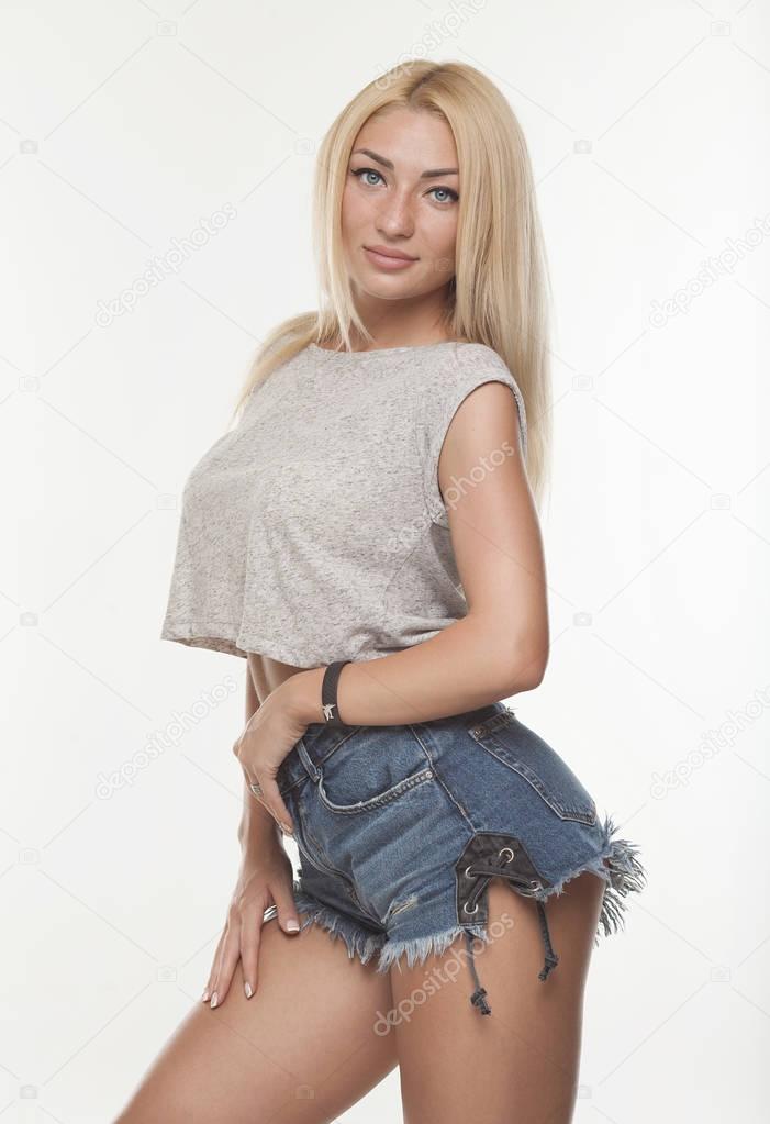Young sexy blond woman in jeans shorts isolated on white