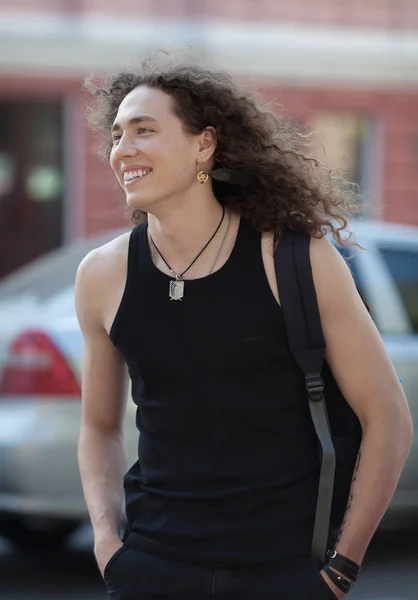 Schöner Mann, der auf der Straße lächelt. lange lockige Haare Mann. — Stockfoto