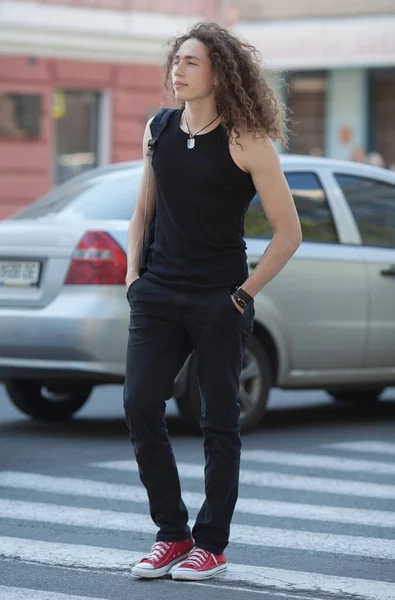 Außenporträt des modernen jungen Mannes zu Fuß Straße. Mann mit langen lockigen Haaren. — Stockfoto