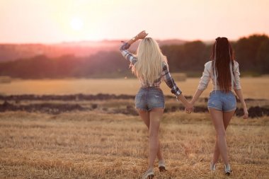 İki kız arkadaşım için günbatımı gitmek. Seksi sarışın ve esmer kadın kot şort.