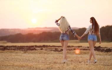 İki kız arkadaşım için günbatımı gitmek. Seksi sarışın ve esmer kadın kot şort.