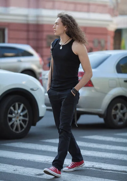 Schöner Mann, der auf der Straße lächelt. lange lockige Haare Mann. — Stockfoto