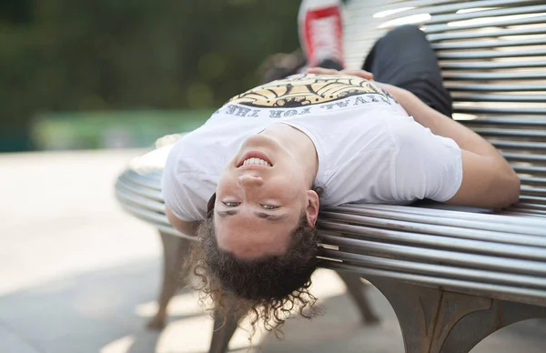 Joven que se relaja en el banco del parque en un día de verano — Foto de Stock
