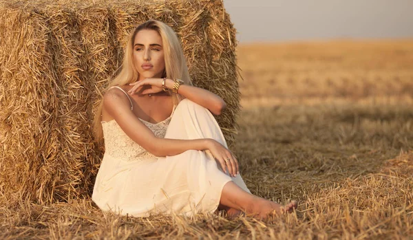 Mulher elegante atraente em vestido de verão branco longo perto de fardo de feno no prado — Fotografia de Stock