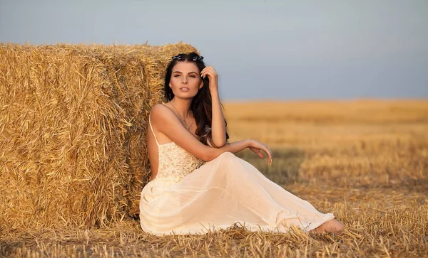 Mulher elegante atraente em vestido de verão branco longo perto de fardo de feno no prado — Fotografia de Stock