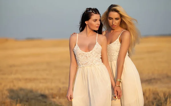 Two Beautiful sexy young women in white dress in a wheat golden field — Stock Photo, Image