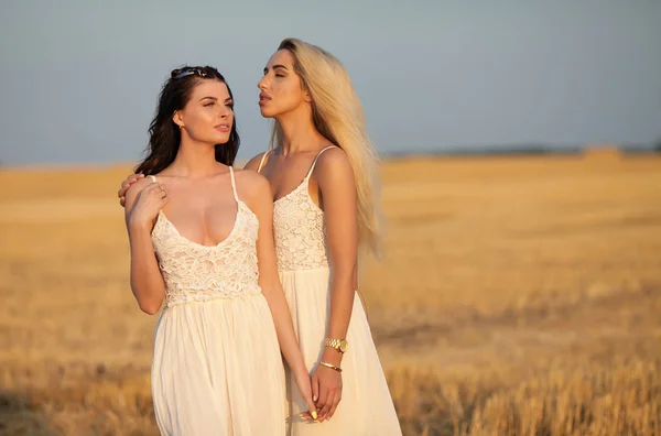 Two Beautiful sexy young women in white dress in a wheat golden field — Stock Photo, Image