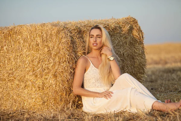 Mulher elegante atraente em vestido de verão branco longo perto de fardo de feno no prado — Fotografia de Stock