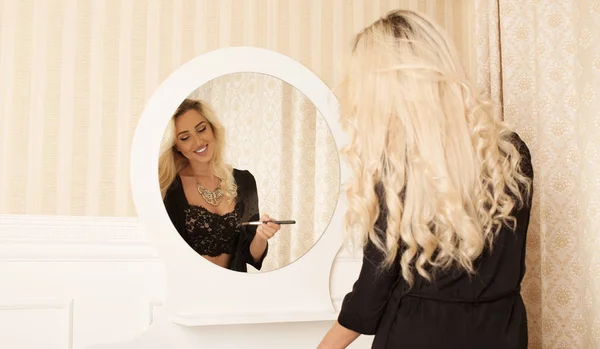 Young sexy blonde woman make up yourself looking mirror