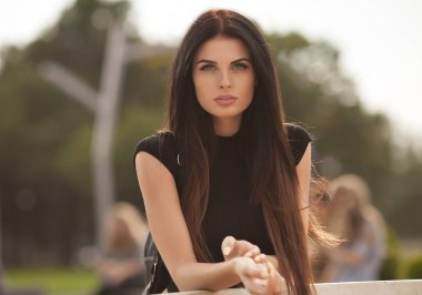 Onun dışında park içinde geçmiş gün batımı ile vaktinizi çekici genç esmer kadın. Beyaz diş.