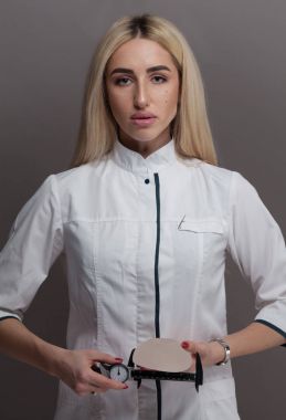 Silikon meme implantı gri arka plan üzerinde tutan plastik cerrah kadın. Plastik cerrahi kavramı