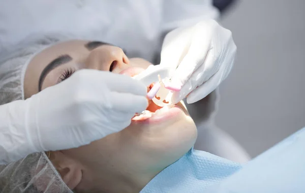 Doctor dentist treats teeth of a beautiful young girl patient. The girl on reception at the dentist. Doctor dentist treats tooth.