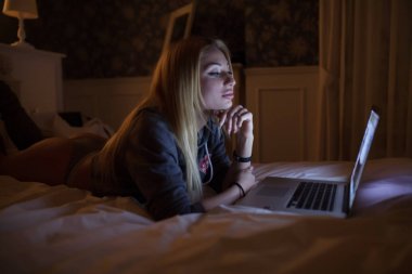 Laptop ile evde yatakta yatarken bir seksi kadın