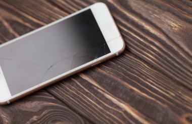 Modern cep telefonu eski ahşap arka plan üzerinde kırık