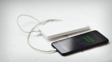 Ahşap masa üzerinde beyaz powerbank ile Smartphone.