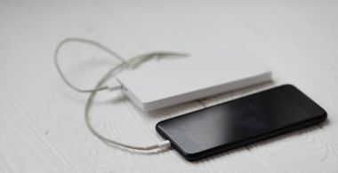 Ahşap masa üzerinde beyaz powerbank ile Smartphone.