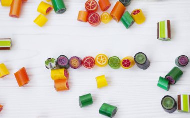 Renkli lolipoplar, baston şekerler ve tatlı şekerler ahşap arka planda karıştırılır.