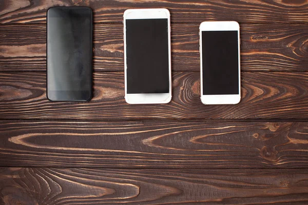 Smart phone on the wooden table, compare size of three mobile phones
