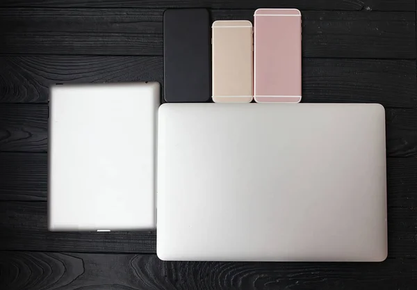 Minimalistic flat lay composition of black & white laptop computer keyboard, cell phone gadget on textured wooden desk table background in bright light. Workspace top view, copy space