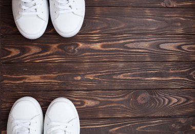 Bir tahta üzerinde beyaz Tuval Ayakkabı çifti. Kahverengi zemin üzerine beyaz spor ayakkabı.