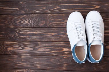Bir tahta üzerinde beyaz Tuval Ayakkabı çifti. Kahverengi zemin üzerine beyaz spor ayakkabı.