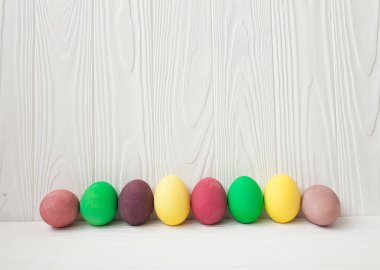 Beyaz ahşap arka plan üzerinde renkli Paskalya yumurtaları.