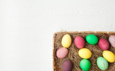Beyaz ahşap arka plan üzerinde renkli Paskalya yumurtaları.