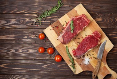 Koyu ahşap masada çiğ biftek..