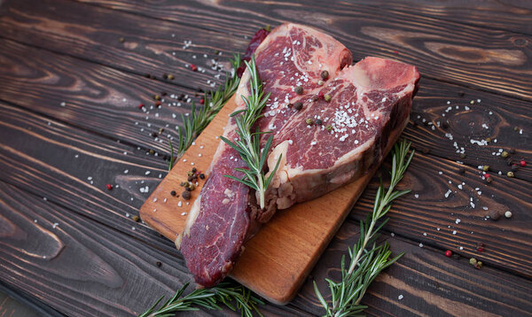 Raw meat steak on dark wooden background ready to roasting