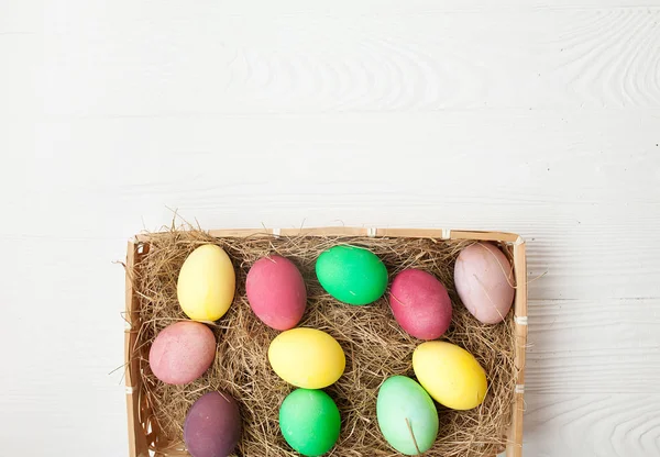 Easter eggs in the nest on white wooden background