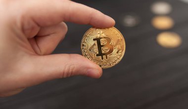 Altın Bitcoin siyah arka planda tutan adamın el