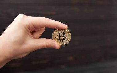 Altın Bitcoin siyah arka planda tutan adamın el