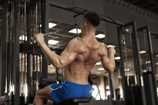 运动员肌肉健美训练模拟器在健身房上回来 — 图库照片