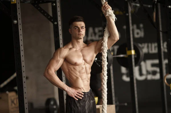 Sporty man with a rope. Photo of young man with perfect body after training. Strength and motivation