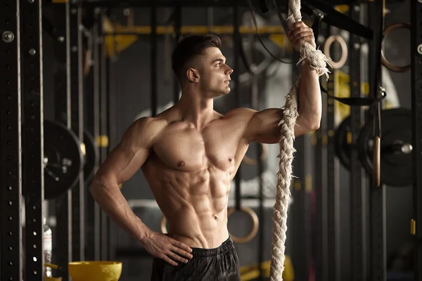 Sporty man with a rope. Photo of young man with perfect body after training. Strength and motivation