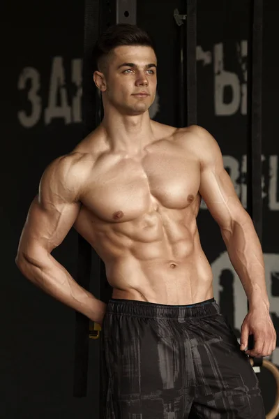Spor salonu ve kasların esneme - güçlü ayakta sağlıklı genç adam kaslı atletik vücut Fitness Model çalışmaları sonra poz