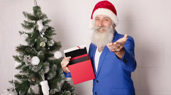 英俊的大胡子男子拿着礼品盒盖着白色的背景 看着相机 圣诞老公公祝您圣诞快乐 新年快乐 穿蓝色西装的男人 圣诞节 — 图库照片