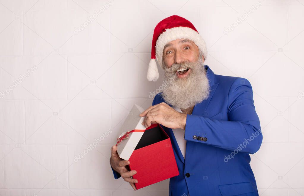 Smiling modern bearded businessman in Santa Hat presenting gift on white