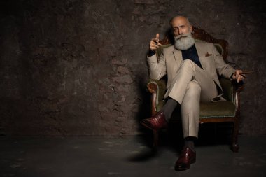 Klasik iç koltukta oturan resmi bir kostüm yakışıklı bir olgun adamın bir portre. Erkek güzelliği, moda.