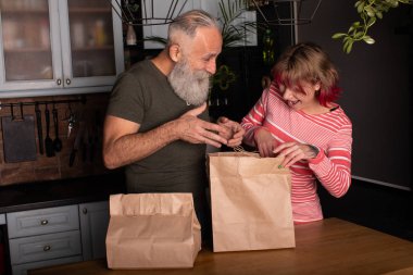 Güzel son sınıf çifti mutfakta yiyecek dolu alışveriş çantalarını boşaltıyor..