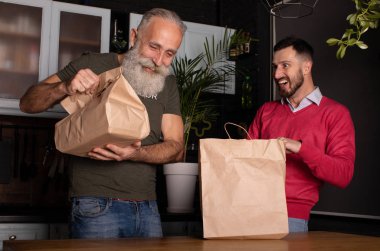 Tüketim, yeme ve insanlar konsepti, iki gülümseyen adam eve paket yemek getiriyor..